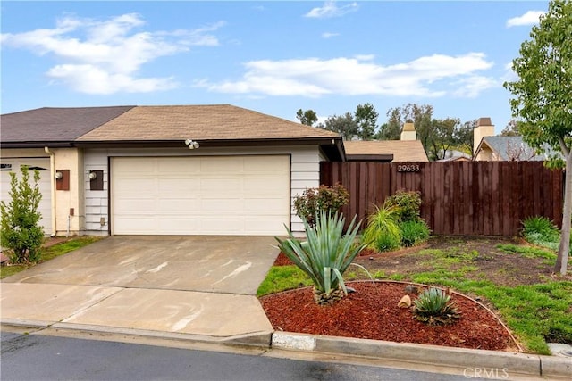 view of front of property with concrete driveway, an attached garage, and fence