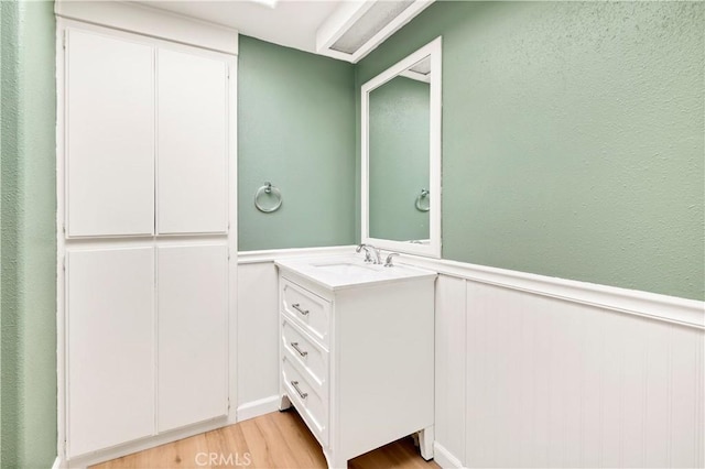 bathroom featuring vanity, wood finished floors, and a wainscoted wall