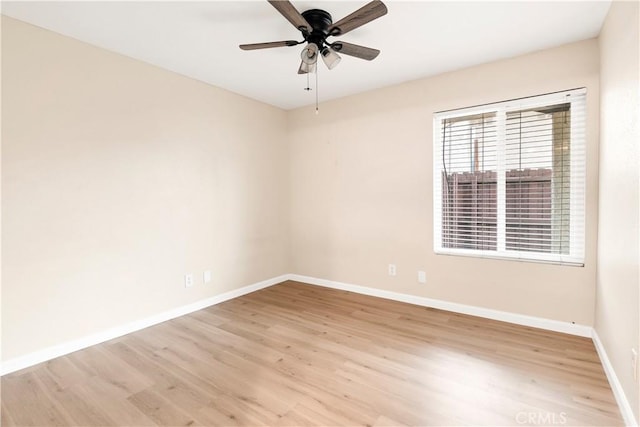 spare room with baseboards, light wood-style floors, and ceiling fan