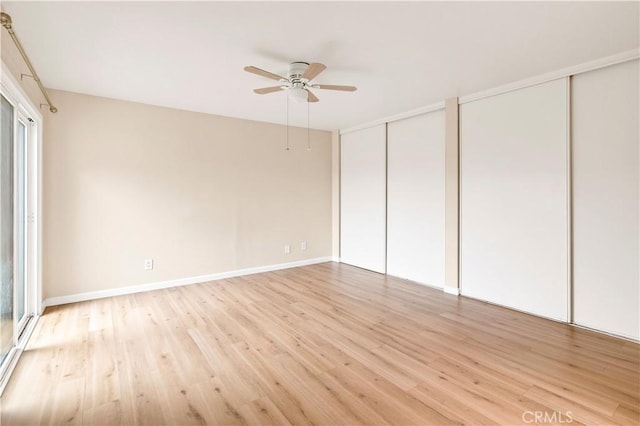 unfurnished bedroom featuring light wood-style floors, baseboards, two closets, and ceiling fan