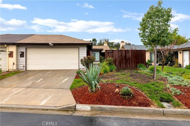 view of front of house with concrete driveway, an attached garage, and fence