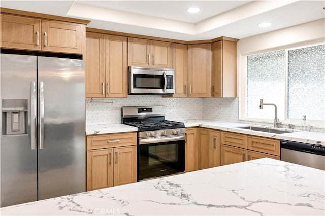 kitchen with light stone counters, appliances with stainless steel finishes, tasteful backsplash, and a sink