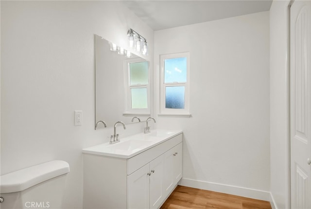 full bathroom featuring wood finished floors, toilet, baseboards, and a sink