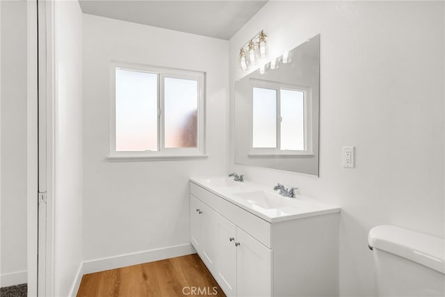 bathroom featuring toilet, wood finished floors, a wealth of natural light, and a sink