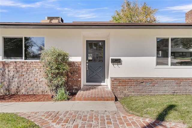 property entrance with stucco siding and brick siding