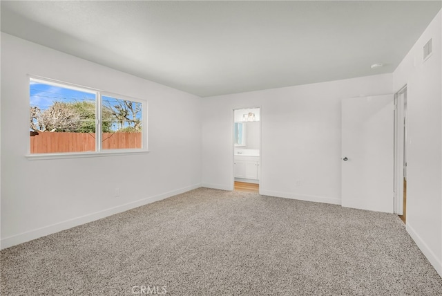 unfurnished bedroom with visible vents, connected bathroom, baseboards, and carpet