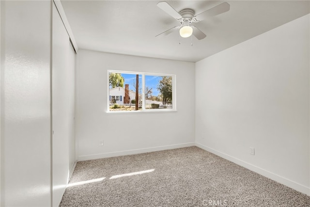 carpeted empty room with baseboards and a ceiling fan