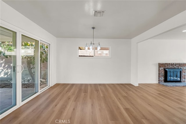 unfurnished dining area with light wood-style flooring, a notable chandelier, baseboards, and visible vents