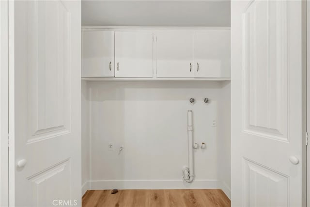 washroom with baseboards, cabinet space, and light wood-style flooring