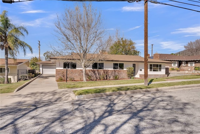 ranch-style house with brick siding, fence, a front yard, driveway, and an attached garage