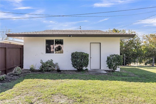 back of property with stucco siding, a lawn, and fence