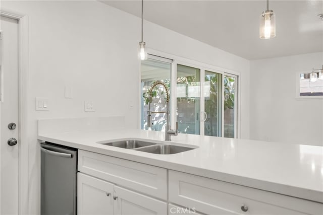 kitchen featuring dishwasher, pendant lighting, light countertops, white cabinets, and a sink