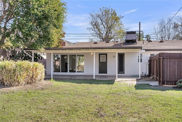 rear view of house featuring central air condition unit, stucco siding, a yard, and fence