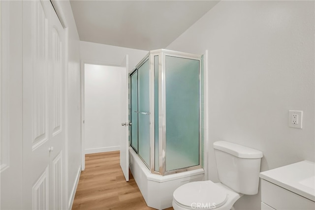 full bath with vanity, toilet, wood finished floors, and bath / shower combo with glass door