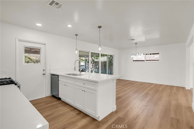 kitchen featuring visible vents, a sink, stainless steel dishwasher, white cabinetry, and a peninsula