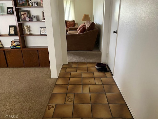 hall featuring dark tile patterned floors and dark carpet