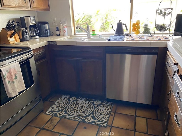 kitchen featuring a sink, tile counters, tile patterned flooring, and stainless steel appliances