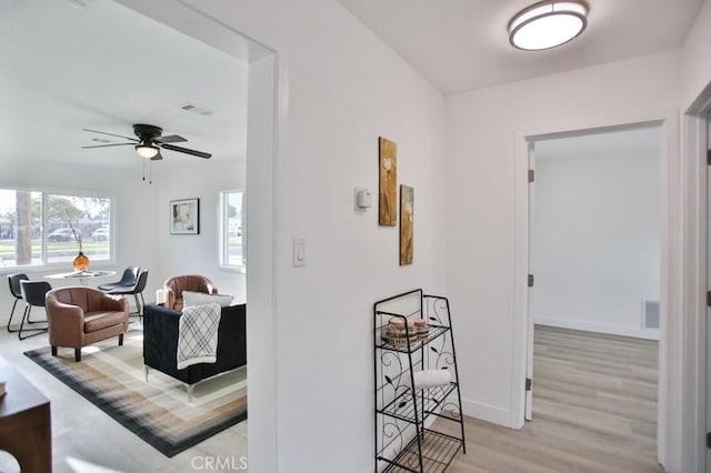 hallway featuring light wood-style flooring, baseboards, and visible vents