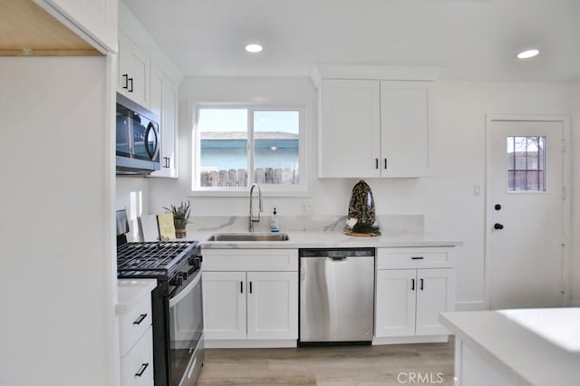 kitchen featuring a sink, light countertops, white cabinets, light wood-style floors, and appliances with stainless steel finishes