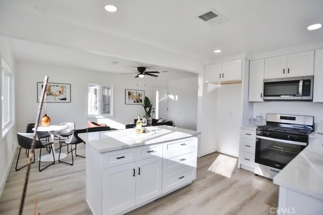 kitchen featuring visible vents, appliances with stainless steel finishes, light wood-style flooring, and white cabinetry