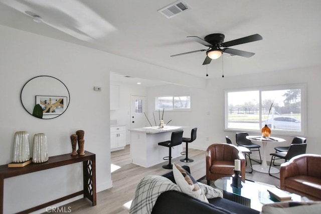 living area featuring visible vents, baseboards, light wood-style floors, and a ceiling fan