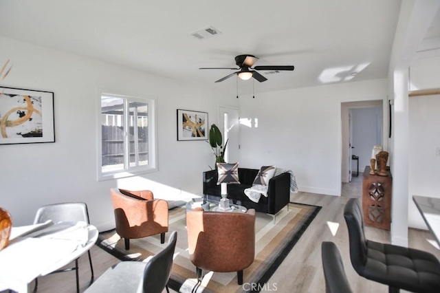 living room with visible vents, baseboards, light wood-type flooring, and ceiling fan