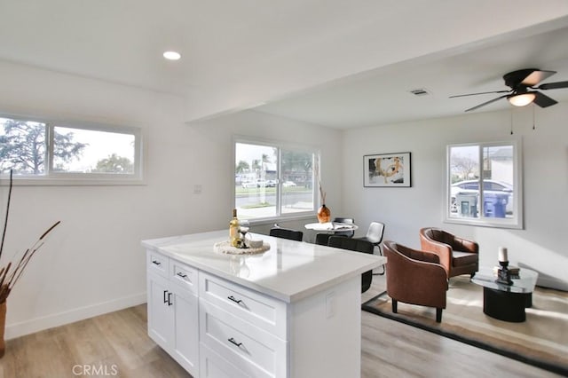 kitchen featuring light wood-style floors, white cabinets, light countertops, baseboards, and ceiling fan