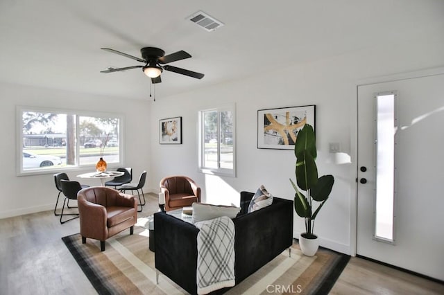 living area with visible vents, baseboards, wood finished floors, and a ceiling fan