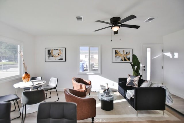 living area with visible vents, baseboards, and a ceiling fan