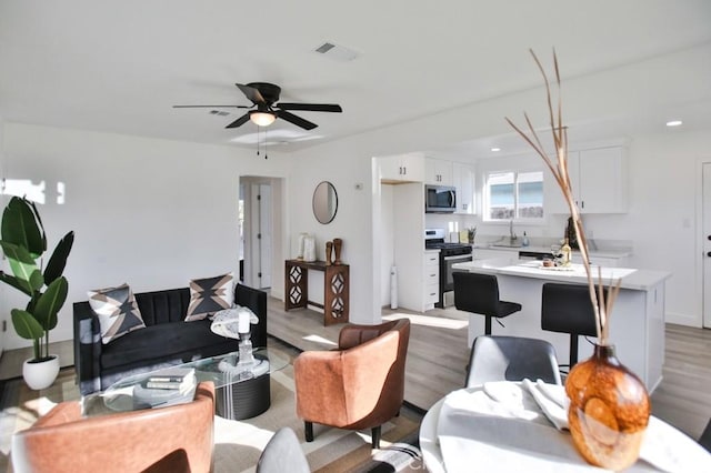 living area with a ceiling fan and light wood-style floors