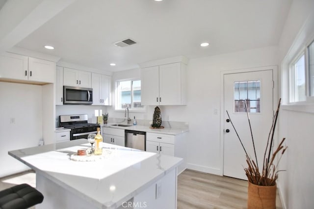 kitchen featuring visible vents, appliances with stainless steel finishes, plenty of natural light, white cabinets, and a sink