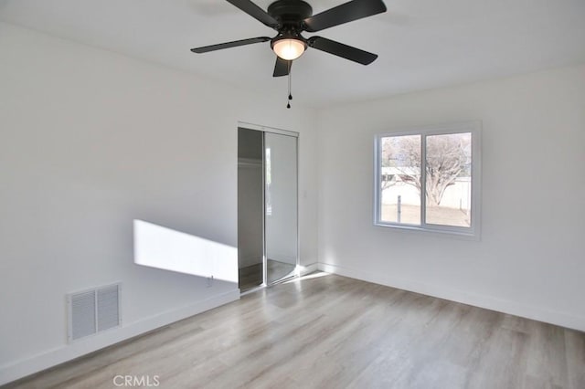 unfurnished bedroom with a closet, visible vents, baseboards, and wood finished floors