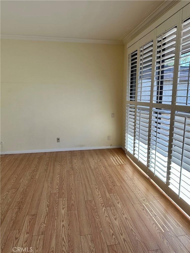 spare room featuring wood finished floors, baseboards, and ornamental molding