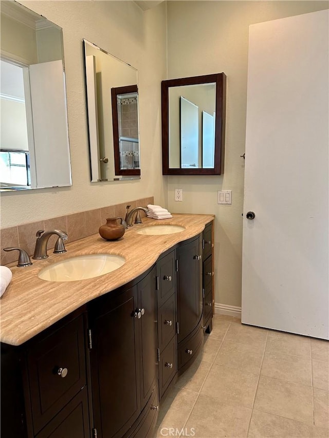 bathroom featuring tile patterned floors, double vanity, baseboards, and a sink