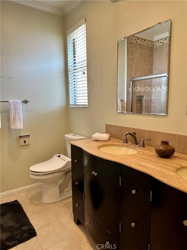 bathroom featuring crown molding, toilet, double vanity, a stall shower, and a sink