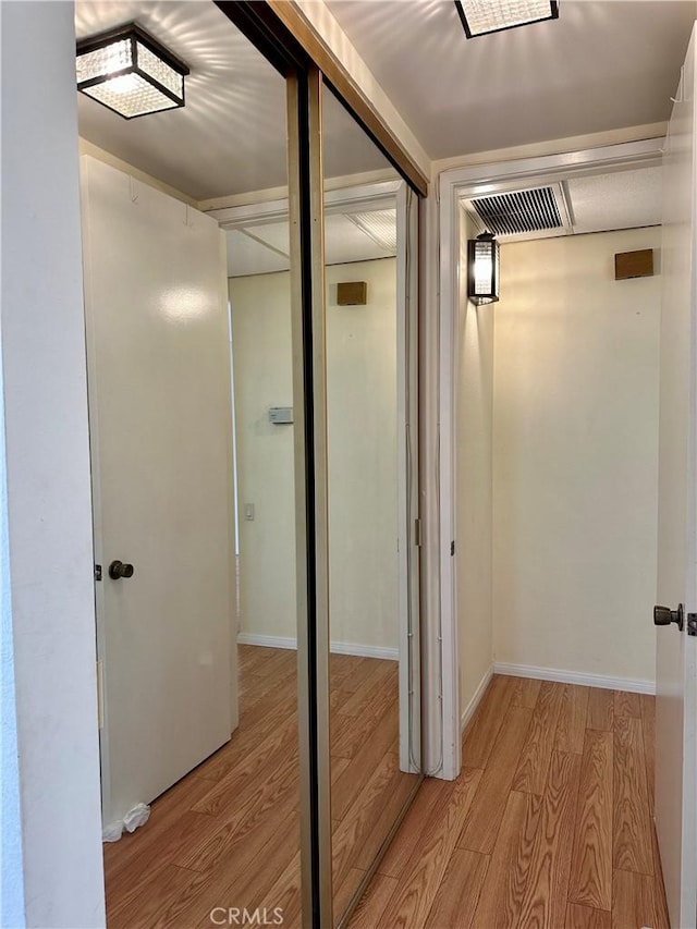 hallway featuring visible vents, baseboards, and light wood-style floors