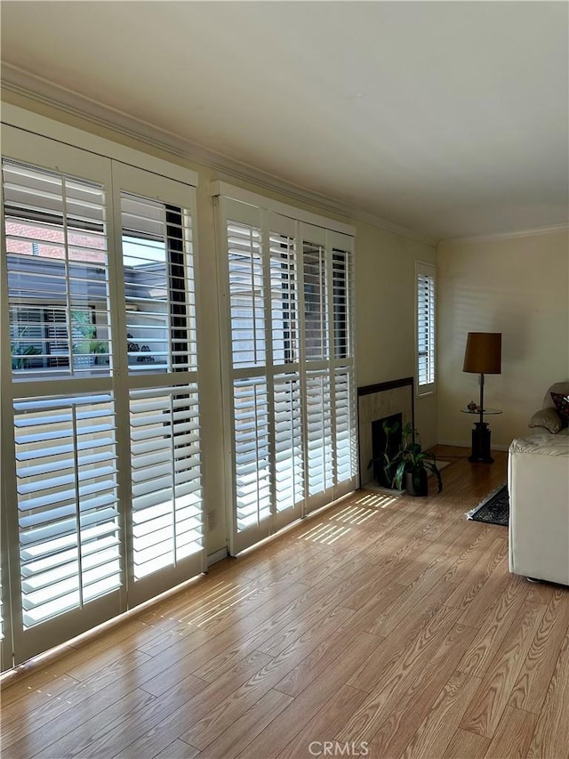 unfurnished living room with crown molding, wood finished floors, and a tile fireplace