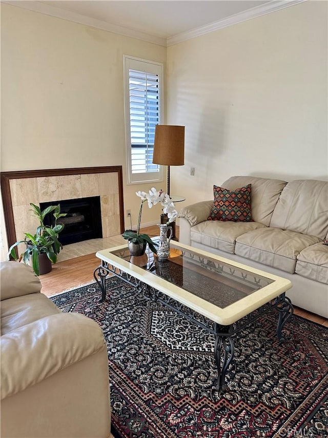 living area featuring a tiled fireplace, wood finished floors, and ornamental molding