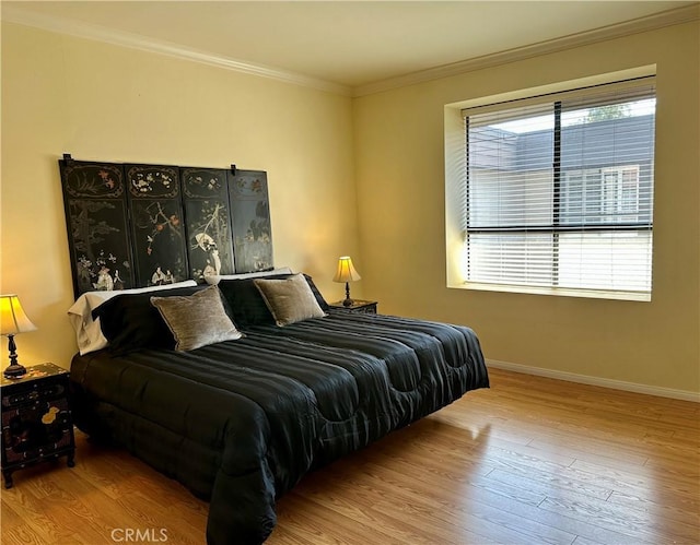 bedroom featuring baseboards, wood finished floors, and ornamental molding