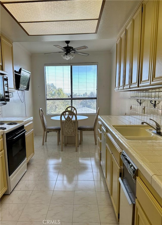 kitchen featuring tile counters, decorative backsplash, white electric stove, a ceiling fan, and a sink