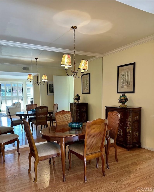 dining space with a chandelier, visible vents, light wood finished floors, and ornamental molding