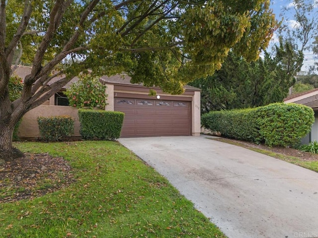 view of front facade with stucco siding, driveway, an attached garage, and a front lawn