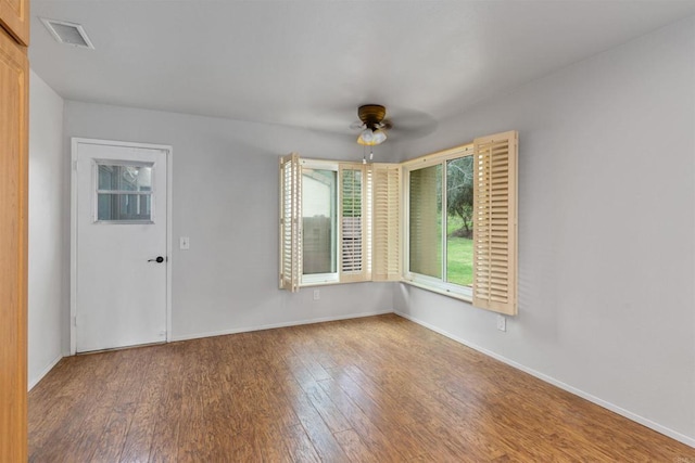 spare room with baseboards, wood finished floors, visible vents, and ceiling fan