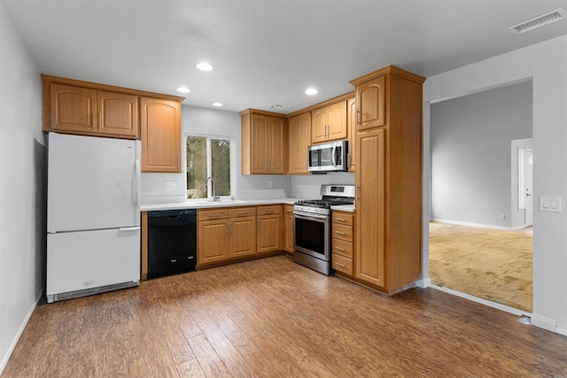 kitchen featuring visible vents, a sink, wood finished floors, appliances with stainless steel finishes, and light countertops