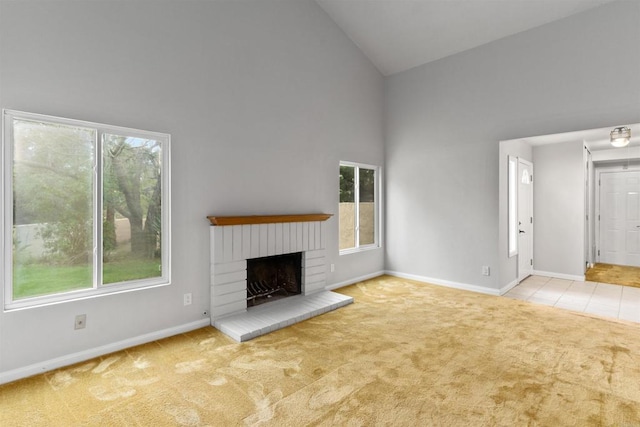 unfurnished living room featuring a brick fireplace, carpet flooring, a healthy amount of sunlight, and high vaulted ceiling