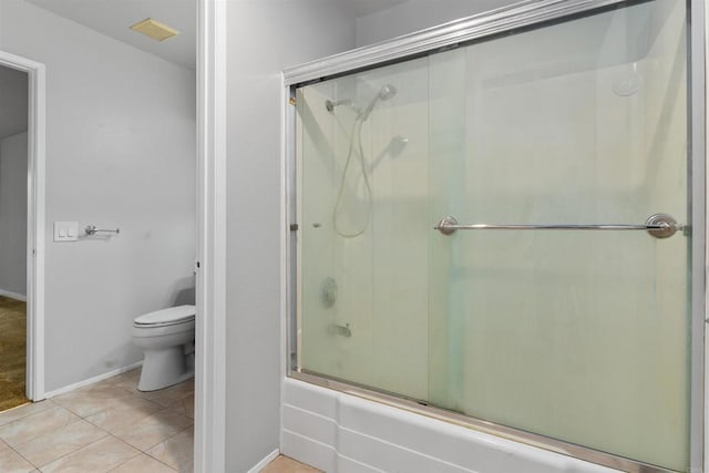 bathroom featuring visible vents, toilet, tile patterned flooring, baseboards, and bath / shower combo with glass door