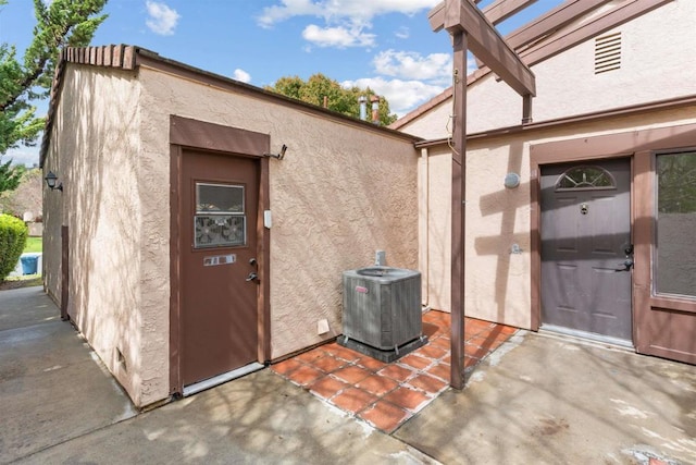 doorway to property featuring central AC unit and stucco siding