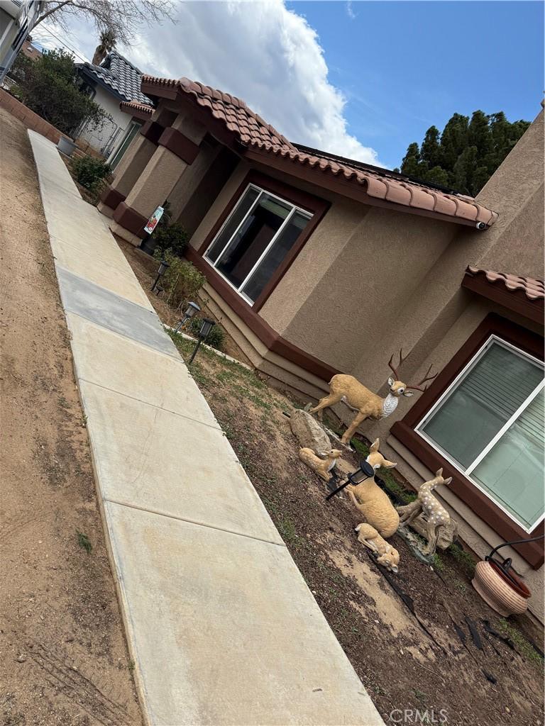 view of side of property featuring stucco siding and a tile roof