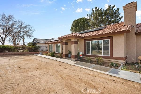 back of property featuring solar panels, a chimney, and stucco siding