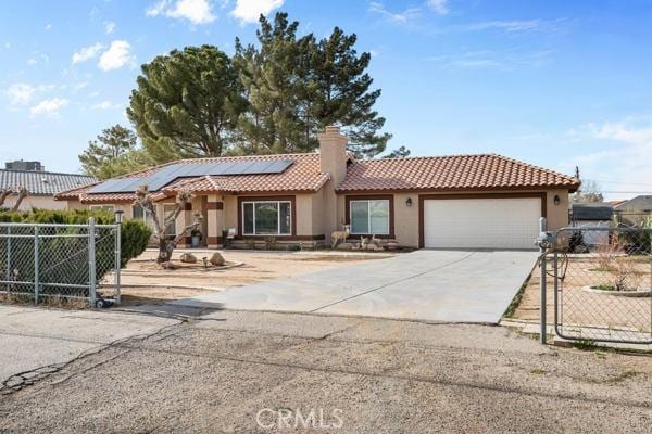 view of front of home with a tile roof, fence, concrete driveway, an attached garage, and solar panels